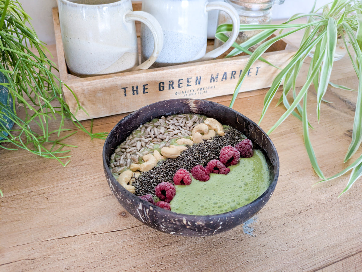 Gros plan sur un smoothie bowl au matcha avec des framboises, des graines et des noix de cajou