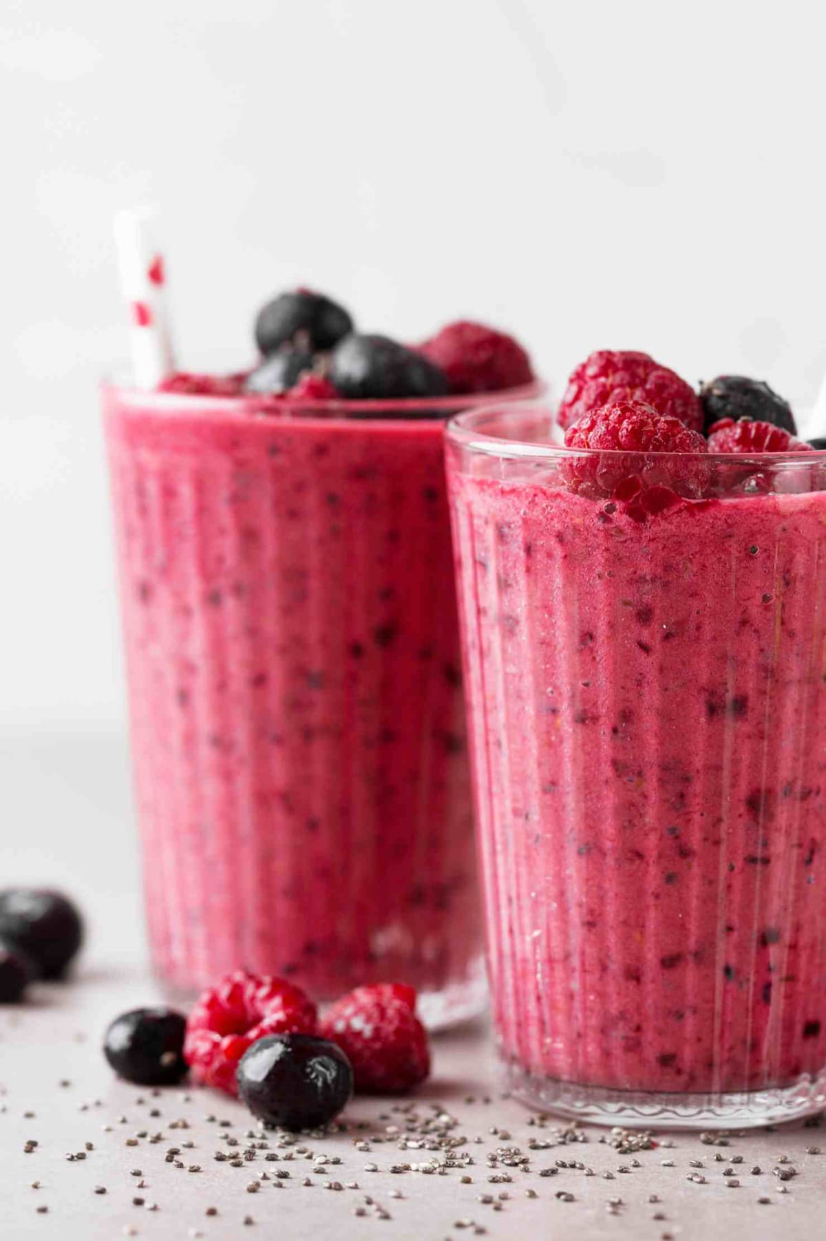 Deux verres de smoothie aux fruits rouges avec des framboises et des myrtilles