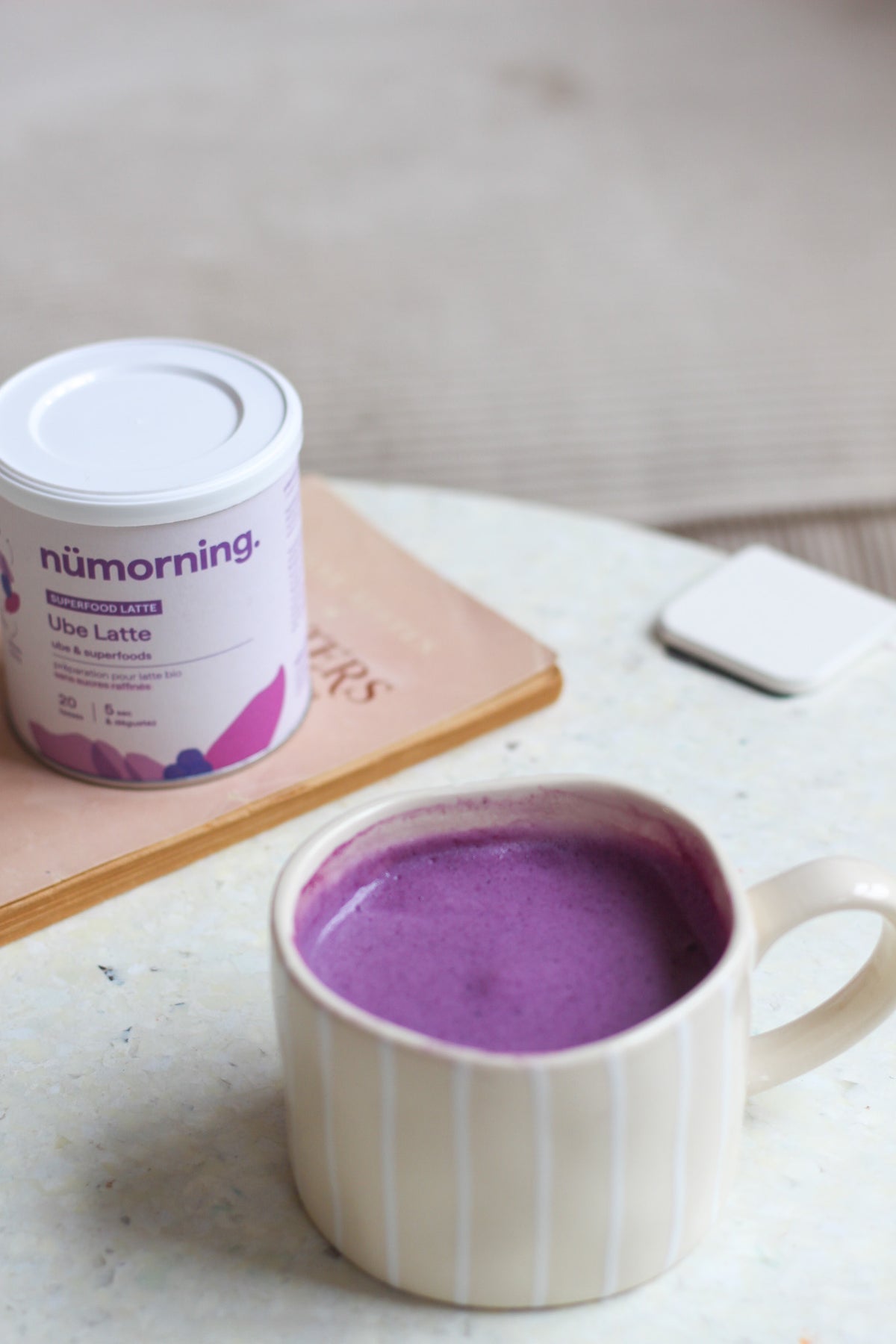 Gros plan sur une tasse de ube latte pour le petit-déjeuner, avec une boite de ube nümorning
