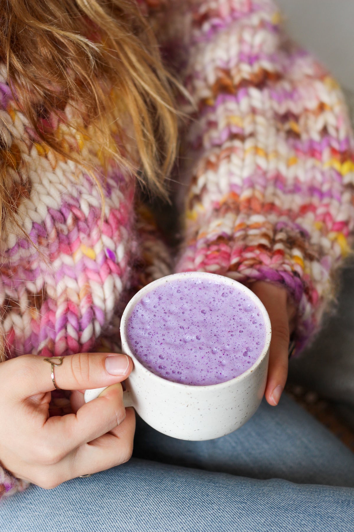 Gros plan sur un mug de ube latte pour le petit-déjeuner, tenu par une jeune femme