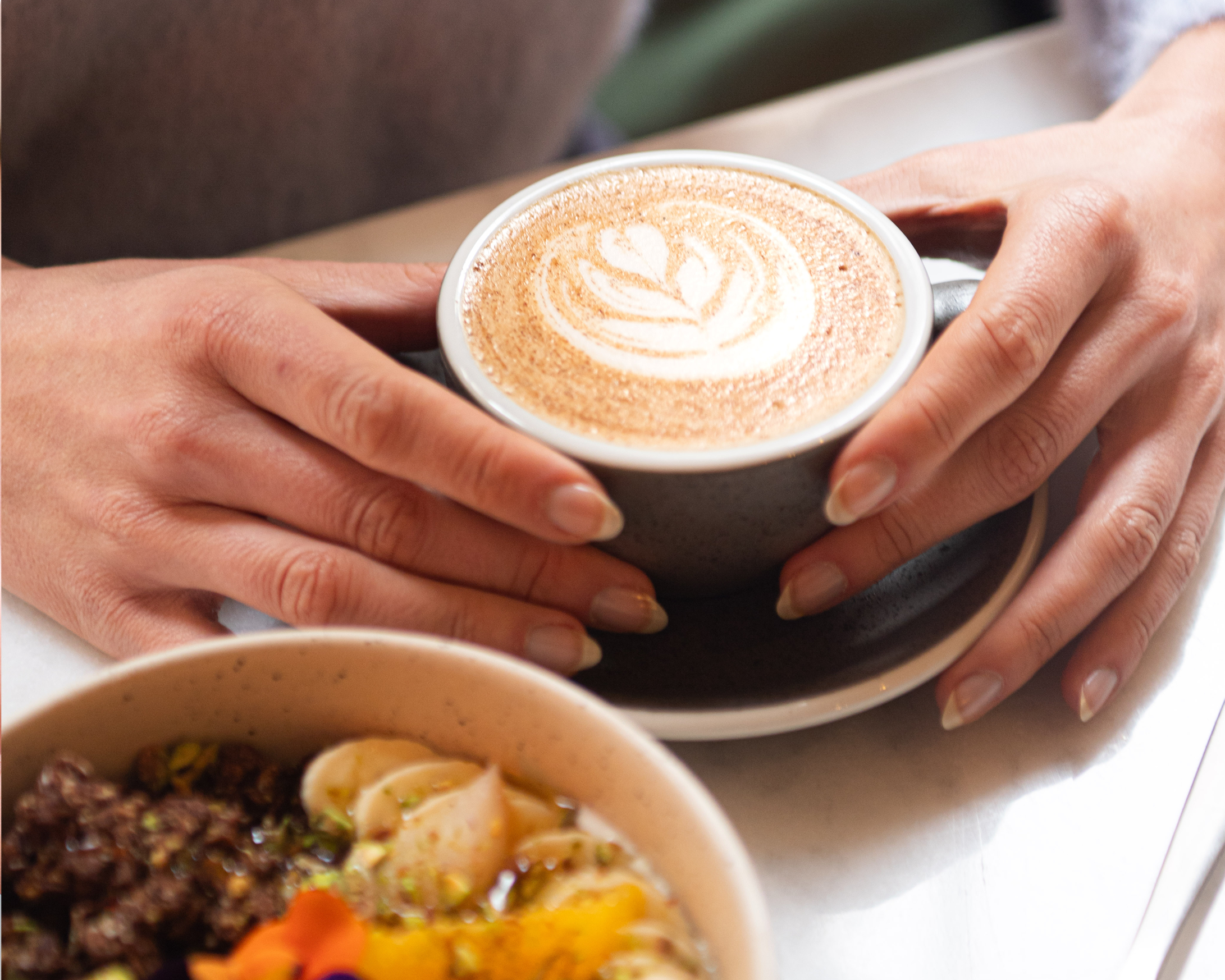 Tasse de latte nümorning accompagnée d’un bol de granola gourmand sur une table lumineuse