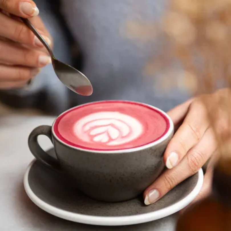 Gros plan sur une tasse de pink chaï avec un art latte à la surface